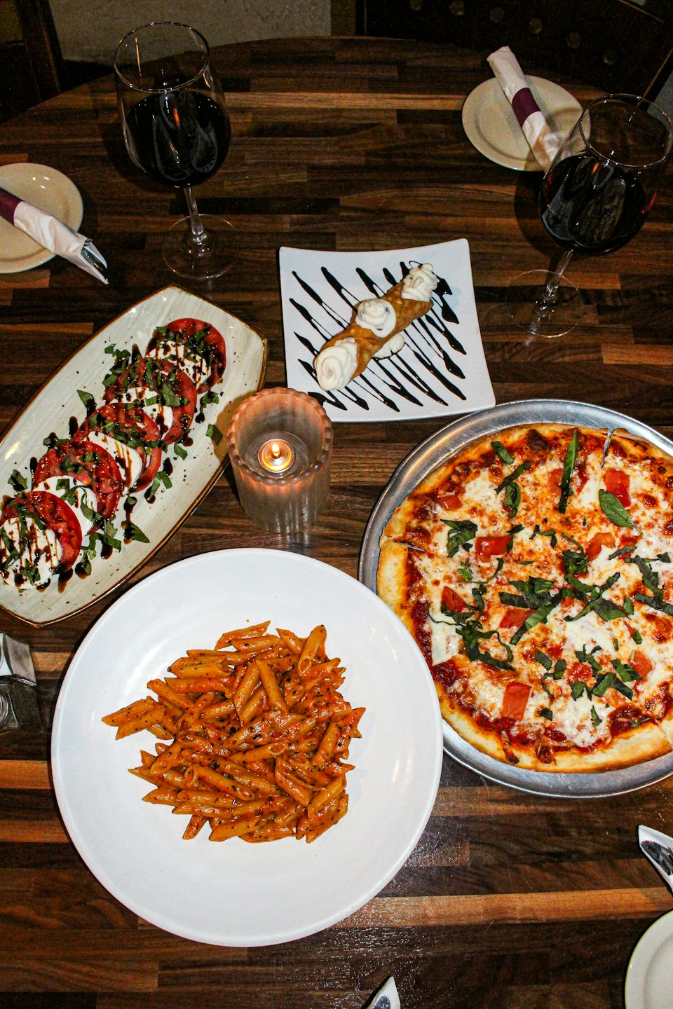 Cibo italiano e vino rosso serviti su un tavolo di legno.