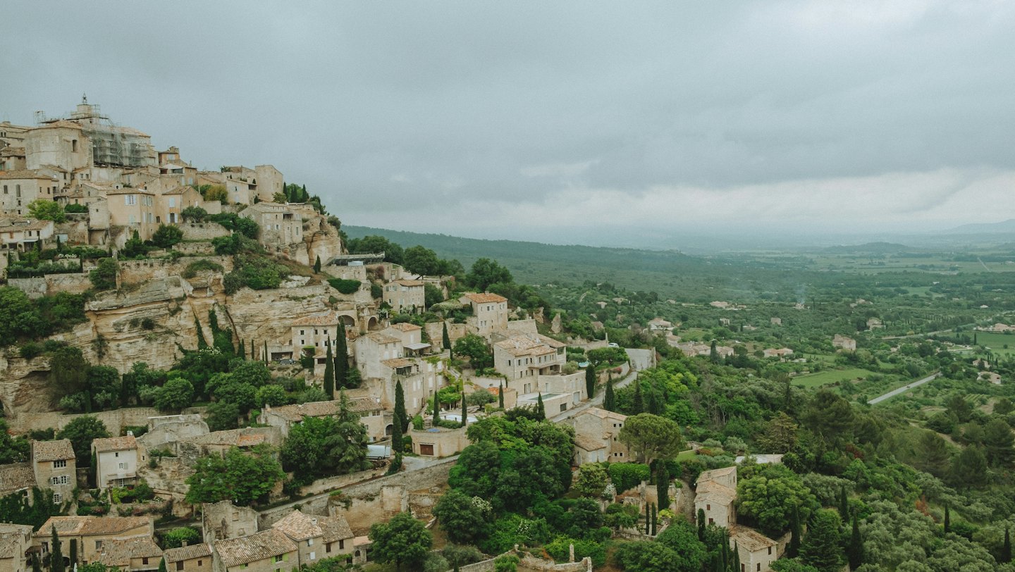 Borgo storico in pietra su un fianco di una collina verdeggiante.