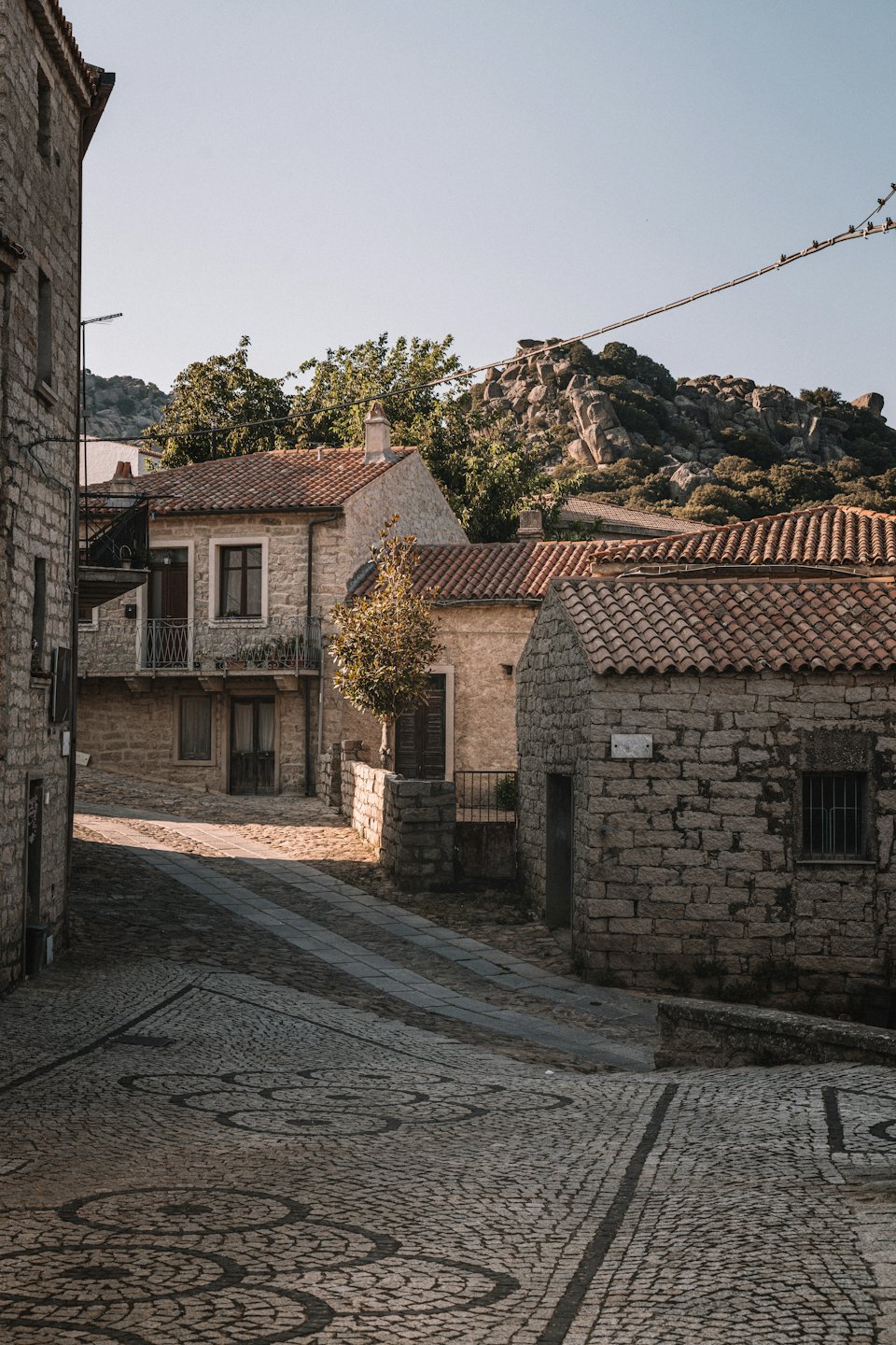 Strada acciottolata illuminata dal sole in un villaggio storico europeo.