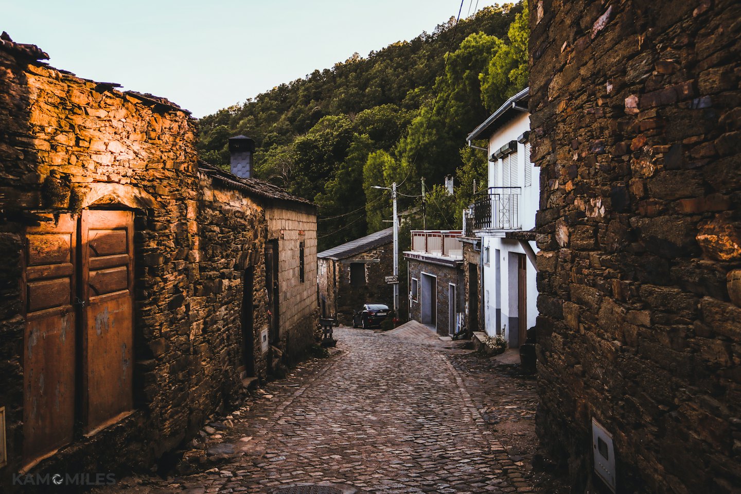 Strada acciottolata che attraversa un villaggio storico in pietra.