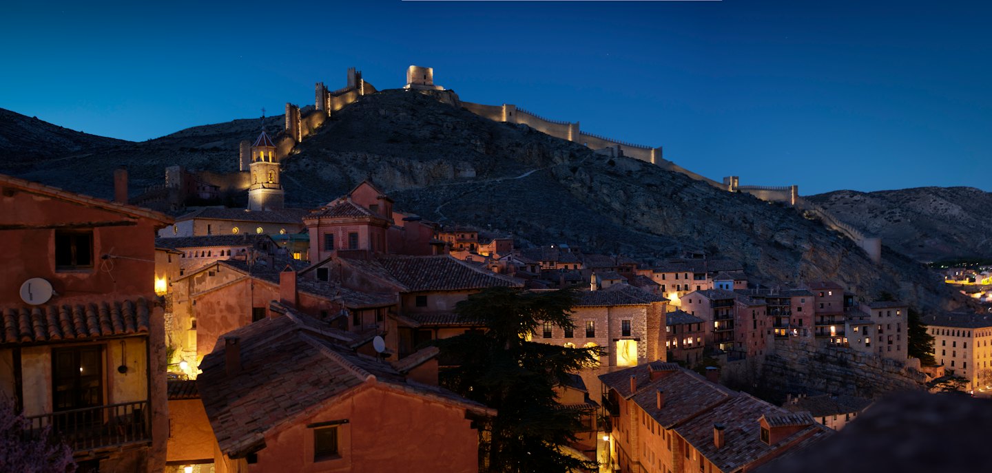 Un villaggio storico si trova sotto un castello luminoso su una collina.