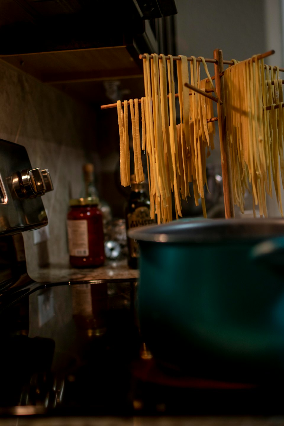 Fettuccine fresche appese a seccare su uno scaffale di legno.
